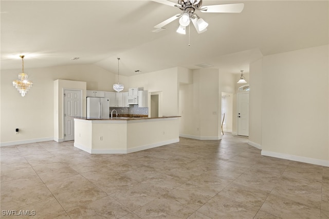 kitchen with white appliances, decorative light fixtures, vaulted ceiling, and white cabinets