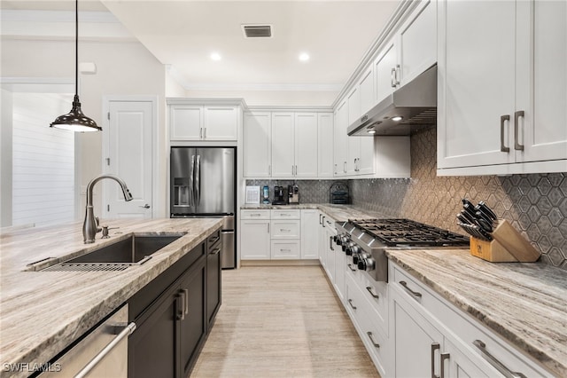 8949 Mustique Ln, Naples, FL 34114 - kitchen featuring stainless steel appliances, under cabinet range hood, white cabinets, light stone counters, and pendant lighting