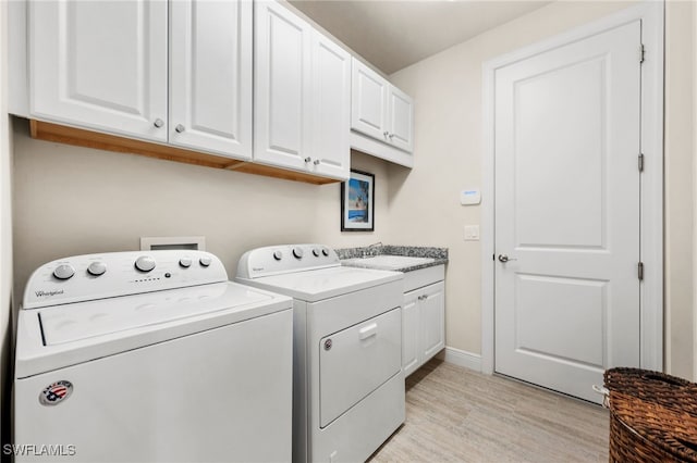 8949 Mustique Ln, Naples, FL 34114 - laundry area featuring washing machine and dryer, cabinet space, and light wood-style flooring