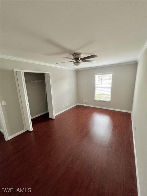 unfurnished bedroom featuring dark wood-type flooring, ceiling fan, crown molding, and a closet