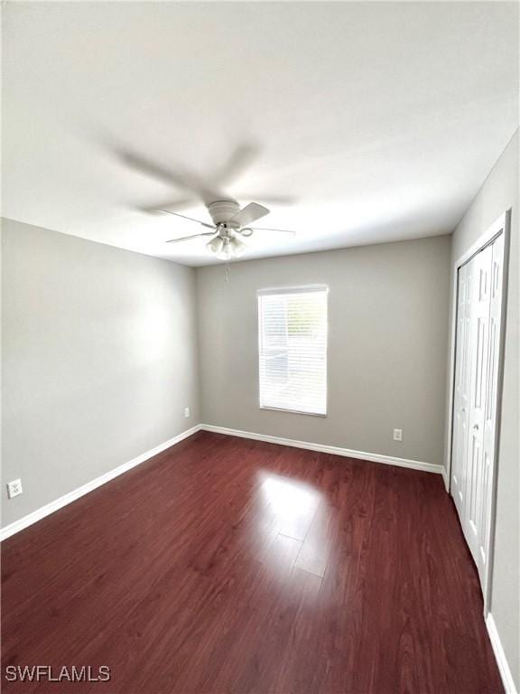 unfurnished bedroom featuring ceiling fan, dark hardwood / wood-style flooring, and a closet