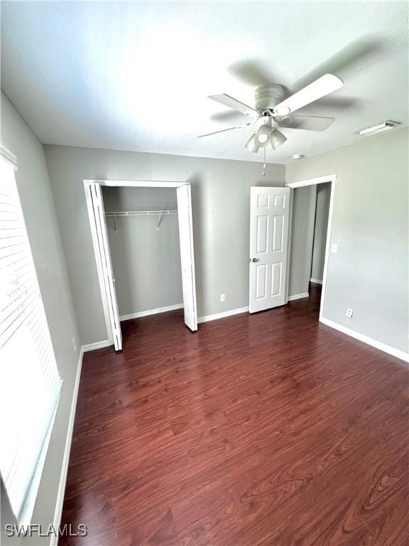 unfurnished bedroom featuring dark hardwood / wood-style floors, ceiling fan, and a closet