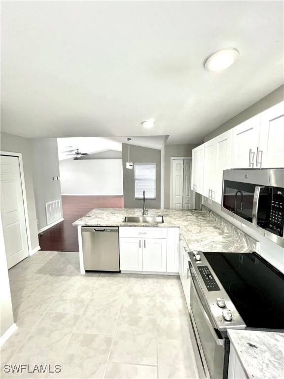 kitchen featuring sink, white cabinetry, kitchen peninsula, stainless steel appliances, and light stone countertops