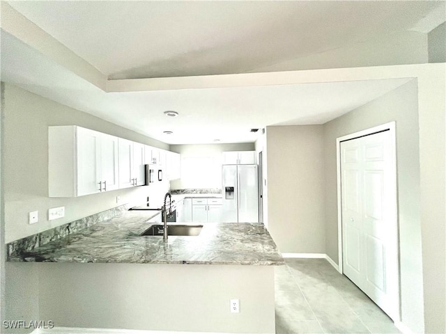 kitchen with white refrigerator with ice dispenser, sink, kitchen peninsula, and white cabinets