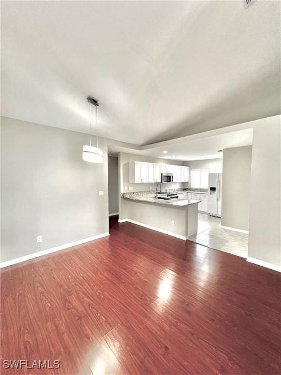 unfurnished living room featuring wood-type flooring and sink