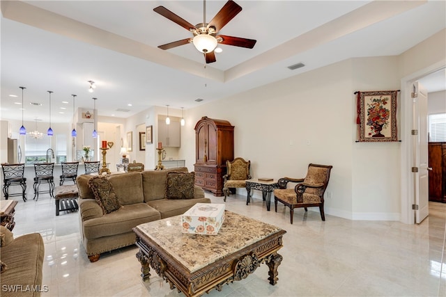 living room featuring a tray ceiling, ceiling fan, and sink