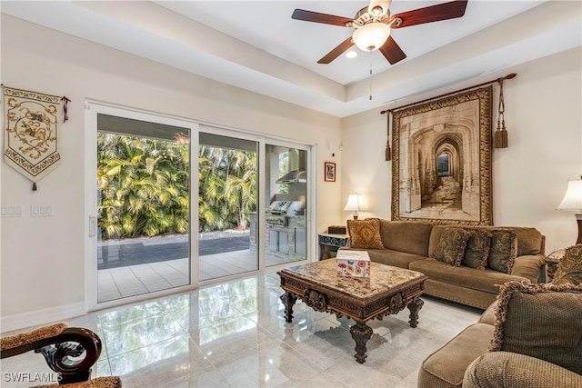 living room with ceiling fan and a raised ceiling