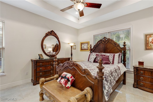 bedroom featuring light tile patterned floors, ceiling fan, and a raised ceiling