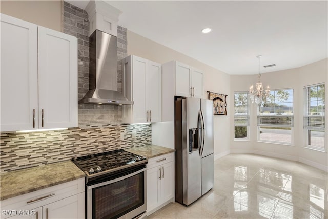 kitchen featuring light stone counters, backsplash, wall chimney exhaust hood, appliances with stainless steel finishes, and a notable chandelier