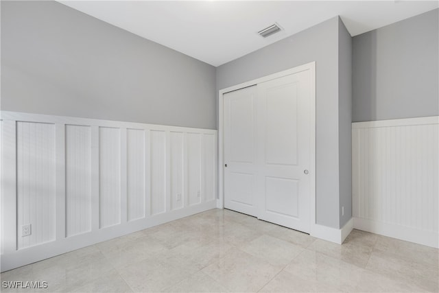 unfurnished bedroom with a decorative wall, visible vents, and a wainscoted wall