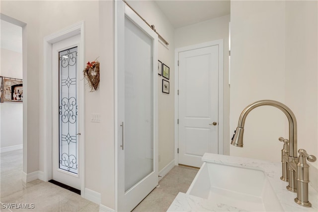 hall featuring baseboards and a sink