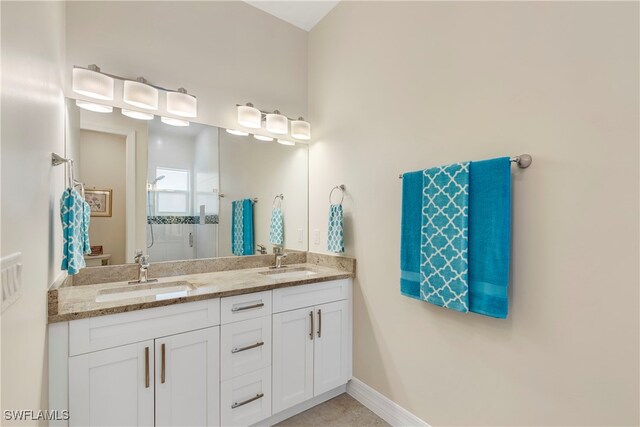 full bath with baseboards, a sink, a shower, and double vanity