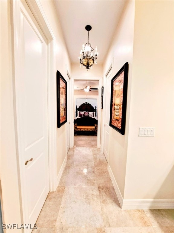 hall with baseboards and an inviting chandelier