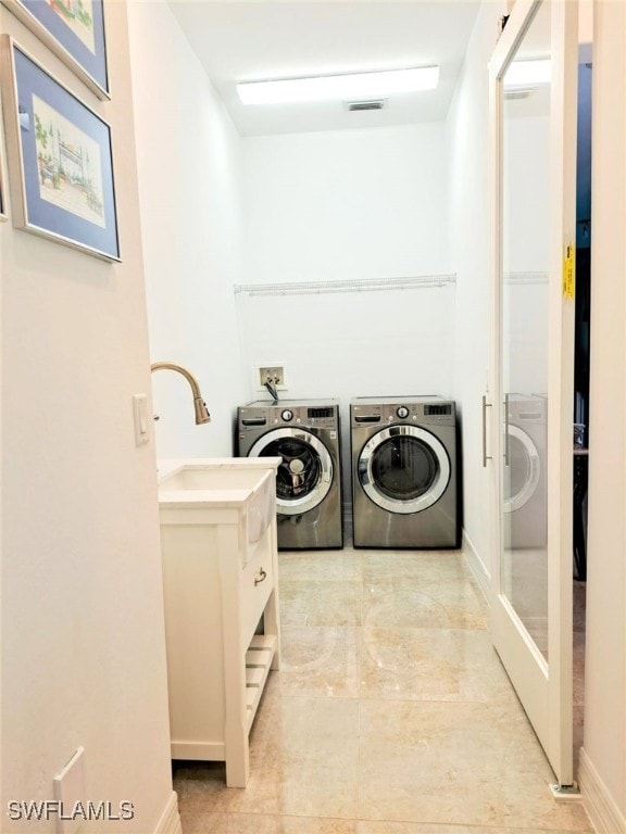 clothes washing area with a sink, washer and dryer, and laundry area