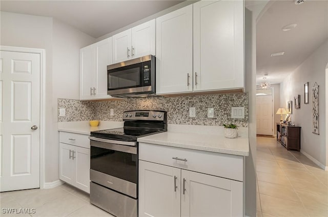 kitchen featuring white cabinetry, appliances with stainless steel finishes, light tile patterned flooring, and decorative backsplash