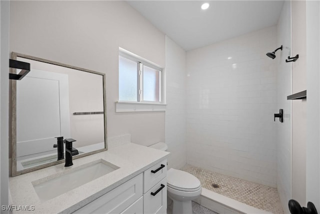 bathroom with vanity, tiled shower, and toilet