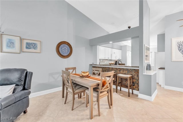 dining room with lofted ceiling, baseboards, and light tile patterned floors