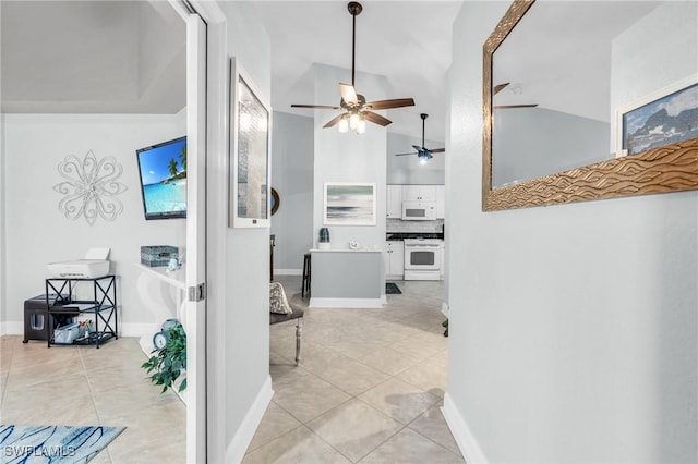 hall featuring light tile patterned floors, vaulted ceiling, and baseboards