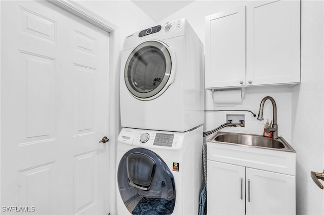 washroom with cabinet space, a sink, and stacked washer and clothes dryer