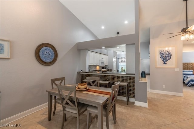 dining area featuring light tile patterned floors, high vaulted ceiling, ceiling fan, and baseboards