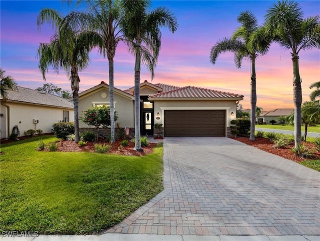 mediterranean / spanish-style home featuring a garage and a lawn