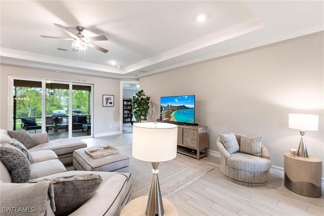 living room with crown molding, ceiling fan, a raised ceiling, and light wood-type flooring