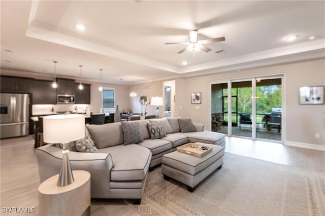 living room featuring a raised ceiling, ceiling fan, and light hardwood / wood-style floors