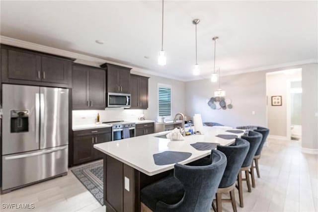 kitchen with appliances with stainless steel finishes, a breakfast bar, decorative light fixtures, sink, and a kitchen island with sink