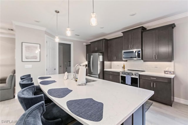 kitchen featuring sink, crown molding, hanging light fixtures, an island with sink, and stainless steel appliances