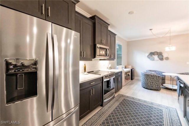 kitchen featuring appliances with stainless steel finishes, tasteful backsplash, ornamental molding, dark brown cabinetry, and light hardwood / wood-style flooring