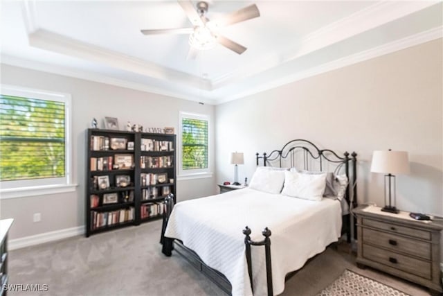 carpeted bedroom with ornamental molding, ceiling fan, and a tray ceiling