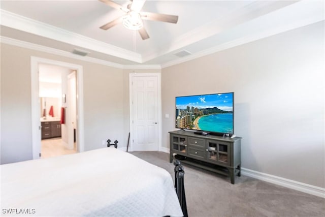 carpeted bedroom featuring ornamental molding, a raised ceiling, ceiling fan, and ensuite bathroom