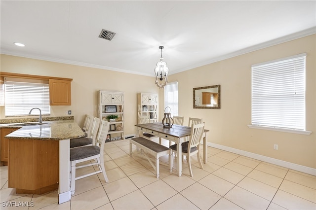 dining space with crown molding, plenty of natural light, sink, and an inviting chandelier