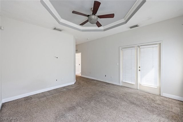 carpeted spare room with ceiling fan, ornamental molding, and a tray ceiling