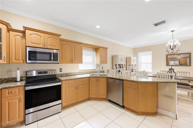 kitchen with appliances with stainless steel finishes, light stone countertops, sink, and hanging light fixtures