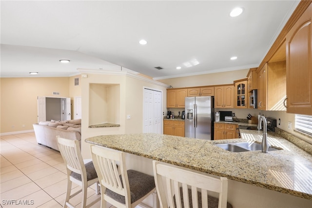 kitchen with sink, appliances with stainless steel finishes, a kitchen breakfast bar, kitchen peninsula, and light stone countertops