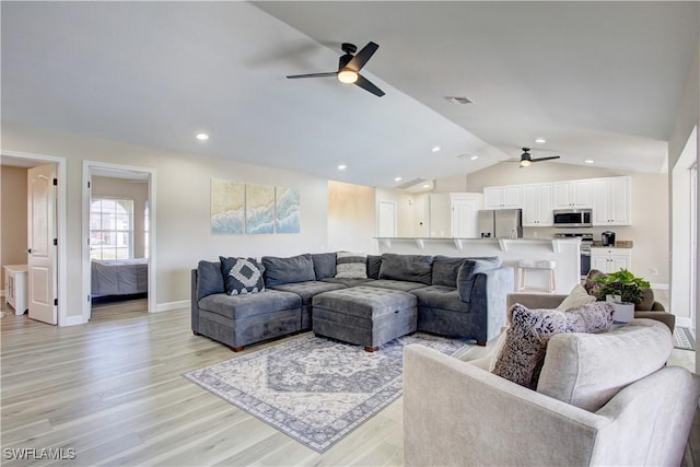 living room with light hardwood / wood-style flooring, ceiling fan, and vaulted ceiling