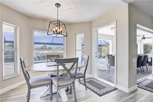 dining room with ceiling fan with notable chandelier and light wood-type flooring