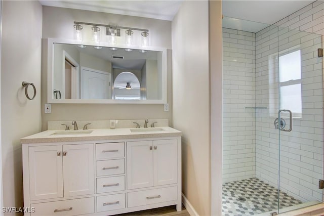 bathroom with ceiling fan, vanity, and a shower with door