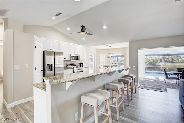 kitchen with white cabinetry, appliances with stainless steel finishes, a large island, and a kitchen bar