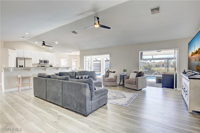 living room with vaulted ceiling, ceiling fan, and light wood-type flooring