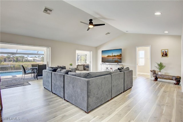 living room with vaulted ceiling, ceiling fan, a healthy amount of sunlight, and light hardwood / wood-style floors