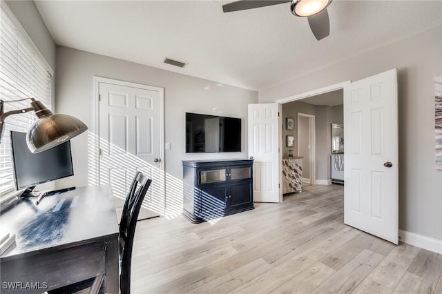 office space with visible vents, light wood-type flooring, a ceiling fan, and baseboards