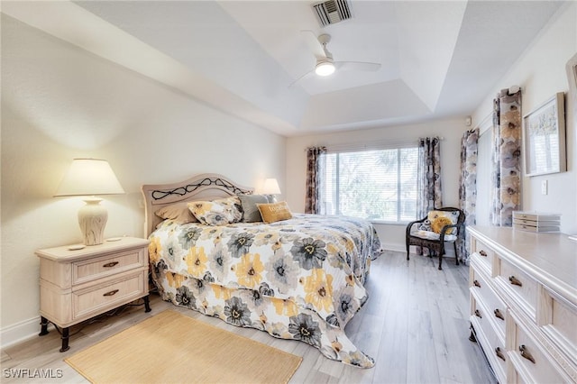 bedroom with a tray ceiling, light hardwood / wood-style flooring, and ceiling fan