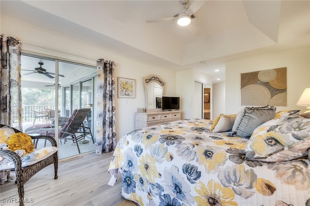 bedroom with ceiling fan, a tray ceiling, light hardwood / wood-style flooring, and access to outside