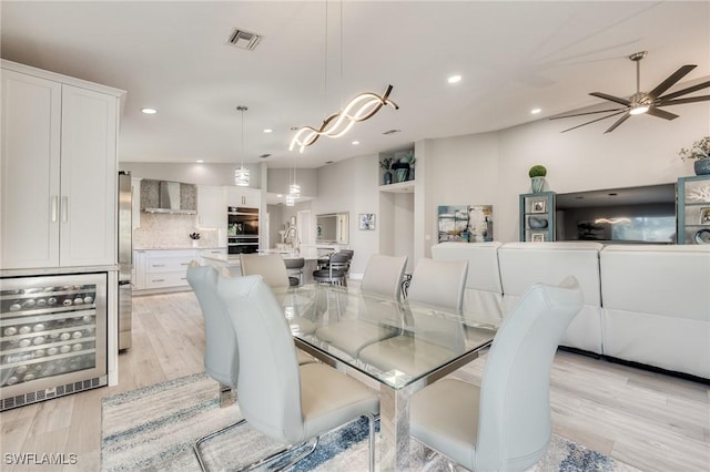 dining room featuring light wood finished floors, visible vents, a ceiling fan, wine cooler, and recessed lighting