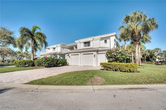 view of front of home with an attached garage, a front lawn, decorative driveway, and stucco siding