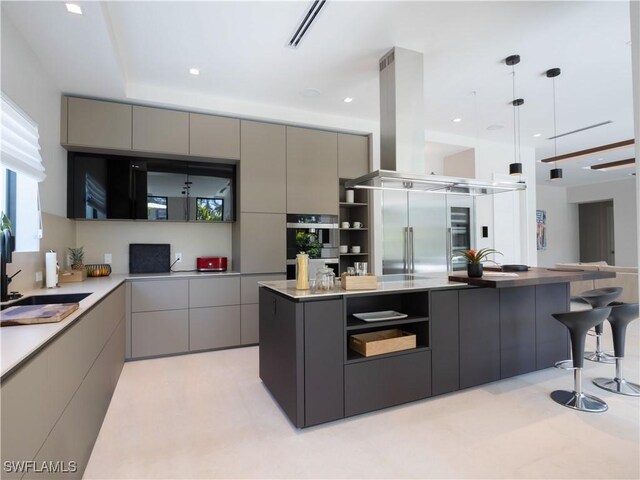 kitchen featuring pendant lighting, gray cabinetry, island range hood, double wall oven, and a kitchen island