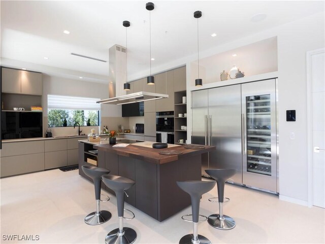 kitchen with gray cabinets, built in refrigerator, a kitchen bar, a kitchen island, and decorative light fixtures