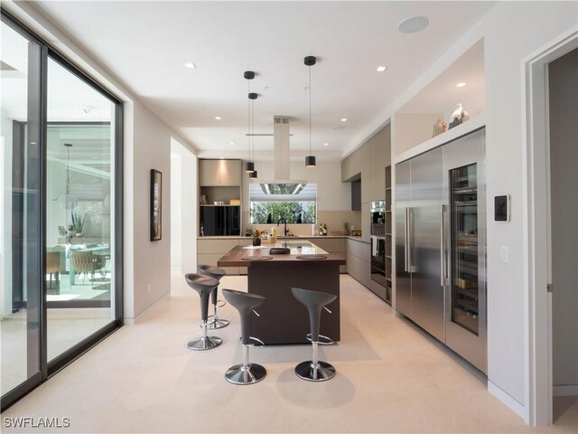 kitchen with built in fridge, a kitchen island, decorative light fixtures, gray cabinetry, and a kitchen bar